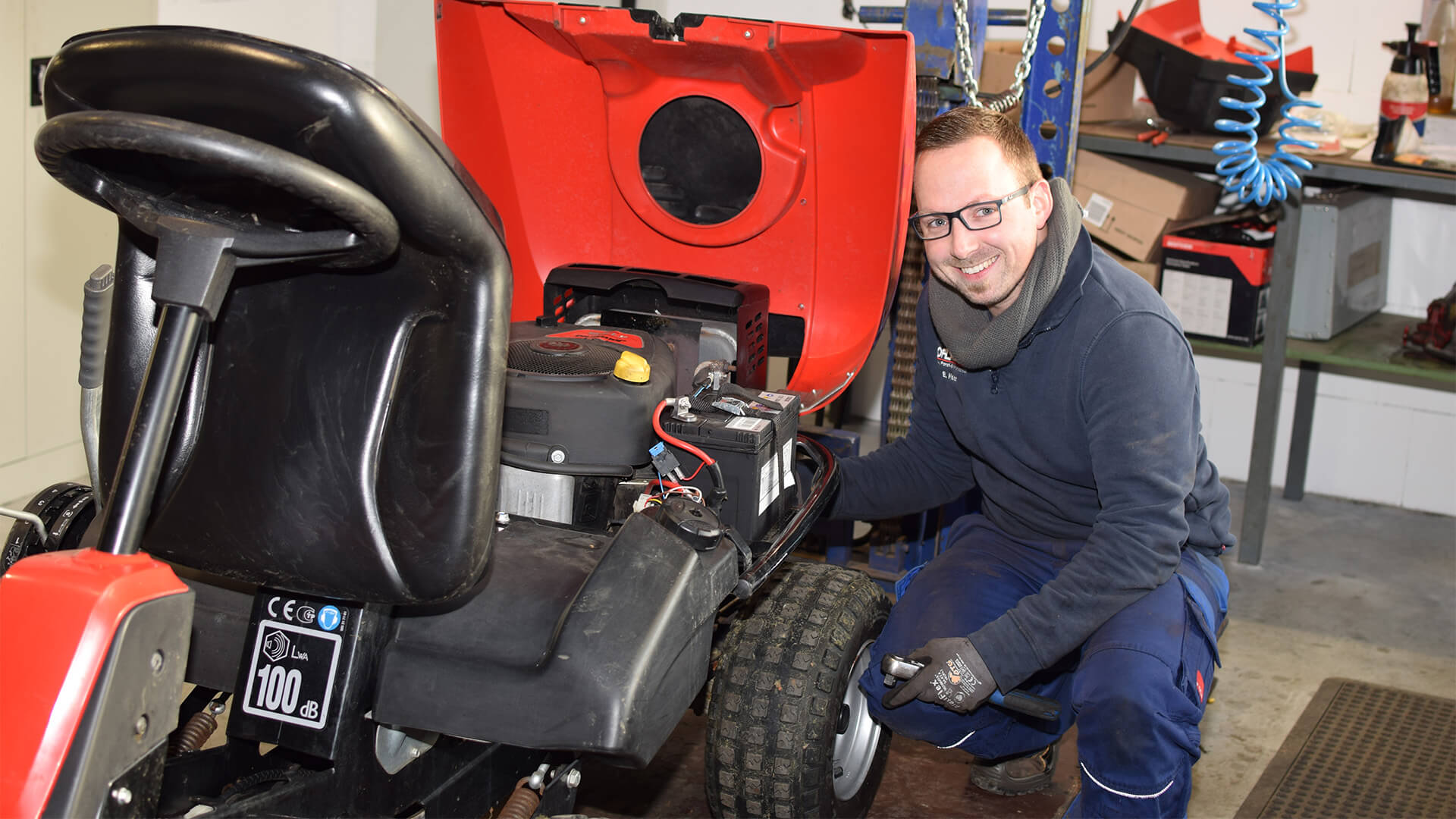 laechelnder mitarbeiter bei horstmann gartentechnik arbeitet an einem rasenmaeher